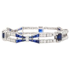 Indulge in the timeless allure of Art Deco with our stunning Blue Sapphire and Diamond Bracelet set in platinum. This exquisite piece embodies the essence of Art Deco design, boasting a perfect blend of quintessential Art Deco symmetry and vibrant contrast. The captivating blue sapphires and dazzling diamonds are meticulously arranged in a symmetrical geometric pattern, echoing the era's iconic style. The focal point showcases three stunning Emerald-cut Blue Sapphires, totaling 4 carats. Complem Timeless Blue Round Bracelets, Luxury White Gold Sapphire Diamond Bracelet, Luxury Sapphire Diamond Bracelet For Formal Events, Luxury Sapphire Diamond Bracelet For Formal Occasions, Luxury Blue Diamond Bracelet With Brilliant Cut, Luxury Sapphire Tennis Bracelet, Blue Diamond Bracelet With Brilliant Cut Luxury Style, Formal Blue Diamond Platinum Bracelet, Blue Diamond Platinum Bracelet For Formal Occasions