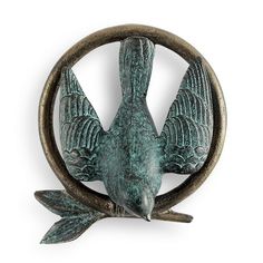 a green metal bird sitting on top of a circular object with wings spread around it's body