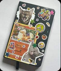 an open notebook with stickers and pictures on the cover, featuring a cat's face