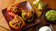 three peppers stuffed with chili and cheese on a plate next to guacamole