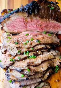 sliced steak on a cutting board with green onions