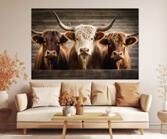 three cows with long horns are standing in the living room together, one is looking at the camera