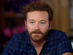 a man with curly hair and beard wearing a blue shirt