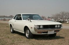 an old white car is parked in the grass