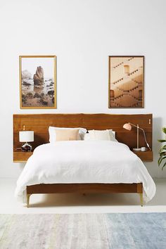 a white bed sitting next to a wooden headboard in a bedroom on top of a rug