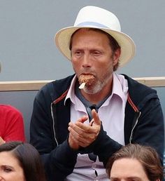 a man eating something while sitting next to other people