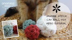 a cat sitting on top of a basket next to crochet balls