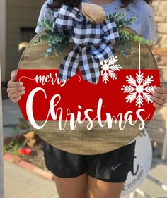 a woman holding a wooden sign that says merry christmas