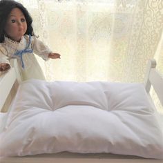 a doll sitting on top of a white bed