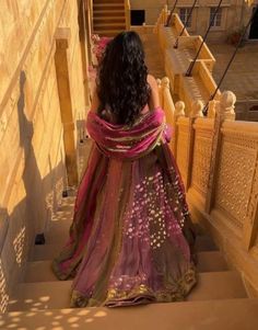 a woman in a purple and pink dress walking up stairs