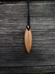 a wooden surfboard hanging from a black cord on a wooden table with wood planks