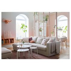 a living room filled with lots of furniture next to two large windows and potted plants