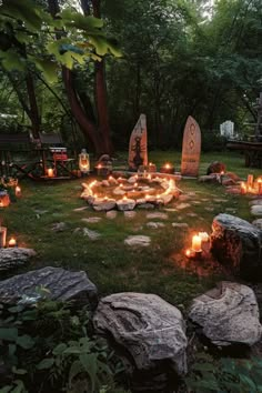 an outdoor area with rocks and candles in the center, surrounded by trees on either side