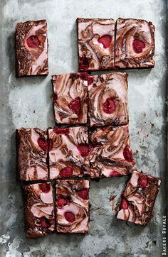 square brownies with raspberries and chocolate frosting arranged on a baking sheet