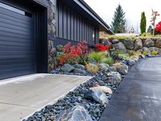 a driveway with rocks and flowers next to a garage