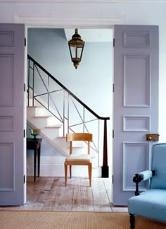 an open door leading to a hallway with luggage on the floor and stairs in front of it