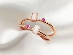 two gold rings with pink stones on white fabric