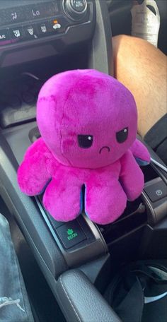 a pink stuffed animal sitting on top of a car dashboard next to a steering wheel