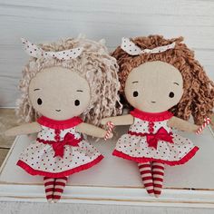 two dolls sitting next to each other on top of a white surface with red and white polka dots