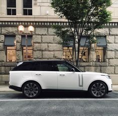 a white range rover parked in front of a stone building