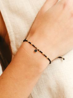 This bracelet of tiny black spinel beads and gold details is decorated with a small black spinel charm. It is a minimalist, simple and elegant bracelet, perfect for any summer event or for everyday wear. Also, it could be perfect as a birthstone gift for August.  It is a fully adjustable bracelet thanks to its good quality nylon cord.  ** M A T C H I N G   C H O K E R ** Don't forget to visit the matching choker in our store! https://www.etsy.com/es/listing/1134766149/elegant-black-necklace-with-gemstone ** D E T A I L S ** Gemstones size we use are black spinel 2mm and black spinel charm 4mm.  Materials: AAA spinel beads, gold filled and good quality nylon.  Our bracelets are adjustable with knots so that you can put them to the measure that you like the most. Gemstones we use in our brac Dainty Black Beaded Bracelets With Tiny Beads, Minimalist Black Beads Bracelet As Gift, Minimalist Black Beads Bracelets As Gift, Minimalist Black Bead Bracelets As Gift, Minimalist Black Beads Bracelet For Gift, Minimalist Black Beaded Bracelets, Simple Black Bracelets As Gift, Simple Black Bracelets For Gift, Simple Black Bracelets For Gifts