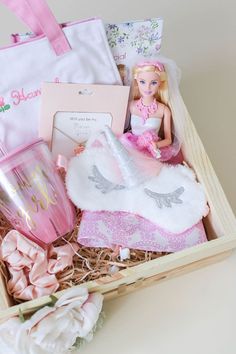 a barbie doll is sitting in a box with other toys and accessories around it on the table