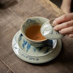 a person is holding a tea cup and saucer