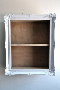 an empty white shelf with two wooden shelves on it's sides, against a wall