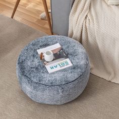 a coffee table with a magazine on it next to a gray ottoman and white blanket