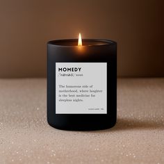 a black candle with a white label on it sitting on top of a wooden table