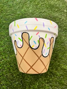 a paper cup with sprinkles and ice cream on it sitting in the grass