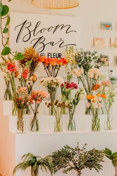 flowers are arranged in vases on the wall next to a sign that says bloom bar and fleur