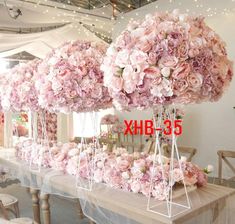 a long table covered in pink flowers and hanging from it's sides with white string lights