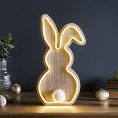 a wooden bunny lamp sitting on top of a table next to some eggs and plants