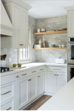 a kitchen with white cabinets and open shelving above the stove is pictured in this image