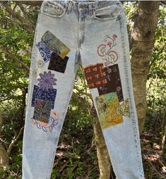 a pair of jeans with patchwork on them hanging from a tree