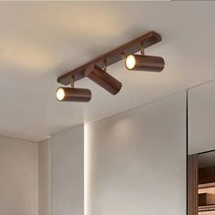 three lights that are on the ceiling in a room with white walls and flooring