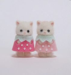 two small white kittens wearing pink and green dresses