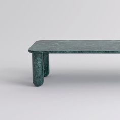 a green marble bench sitting on top of a white floor