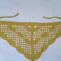 a yellow crocheted triangle on a white background