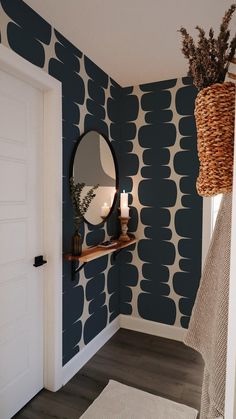 a room with blue and white wallpaper has a round mirror on the wall next to a wicker basket