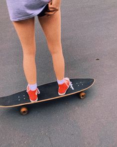 a person standing on top of a skateboard with their feet in the air and wearing red tennis shoes