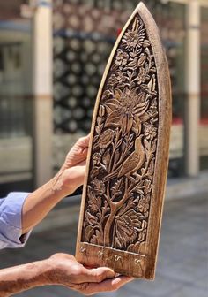 a person holding an intricate wooden object in their left hand and the other hand is holding it with both hands