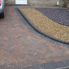 a car parked in front of a house with gravel on the ground and brick edging