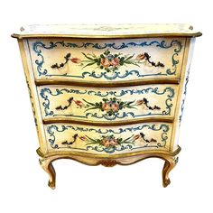 an ornately painted chest of drawers against a white background