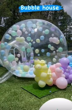 a bubble ball with balloons floating in it on the grass next to some other items