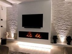 a living room with a large flat screen tv mounted on the wall next to a fire place