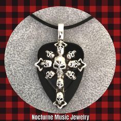 For the love of Goth! 💀 For women and men  Large silver Cross of Skulls Charm on black celluloid and black delrin picks.  Large silver bail.  Solid and sturdy pendant.  Length approx 2 inches.  Style choice:  Stainless Steel Chain 24" Stainless Steel Chain 20" Black leather cord 18" (w/2" ext) Black Rock Style Jewelry For Halloween, Black Jewelry For Halloween Concert, Silver Halloween Concert Jewelry, Silver Jewelry For Halloween Concert, Black Engraved Jewelry For Halloween, Black Rock Style Jewelry For Concerts, Engraved Black Jewelry For Halloween, Handmade Black Jewelry For Concert, Handmade Black Jewelry For Concerts