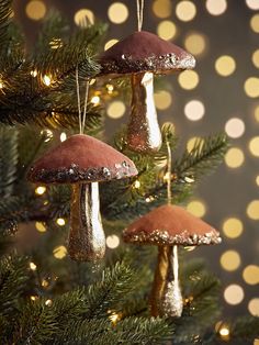 three mushrooms hanging from a christmas tree with gold lights in the backgrounnd