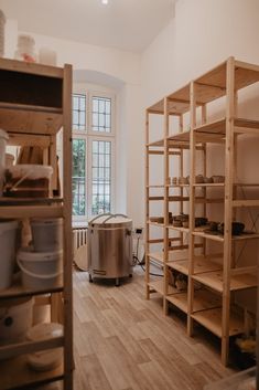 a room filled with lots of wooden shelves next to a metal trash can on top of a hard wood floor